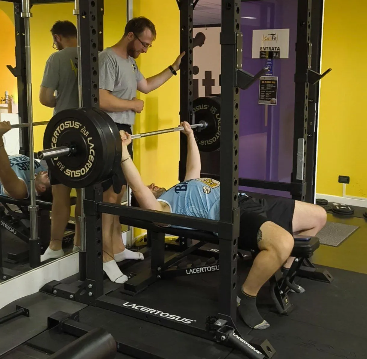 Personal trainer che segue un ragazzo in panca piana
